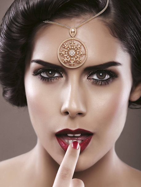 Schönheitsporträt einer brünetten Frau mit rauchigen Augen, roten Lippen und einem Haar-Accessoire. - Foto, Bild