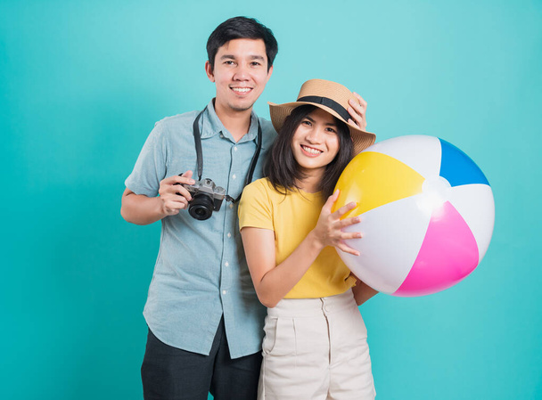 Happy Asian young beautiful woman handsome man couple in summer in holiday travel beach accessories ball and camera isolated on blue background with copy space for text - Фото, зображення