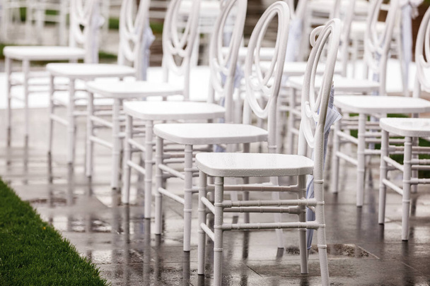 結婚式の前に屋外の白い空の濡れた椅子の行。選択的焦点. - 写真・画像