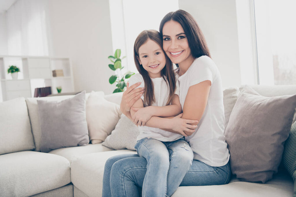 Photo of pretty little girl young charming mommy hugging holding each other close affectionate sitting comfy sofa spend time weekend together indoors home house - Valokuva, kuva