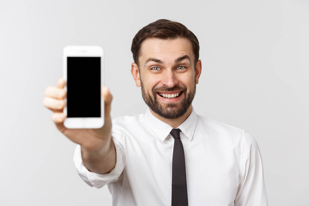 Houkutteleva nuori liikemies osoittaa tyhjä näyttö matkapuhelin valkoisella taustalla
 - Valokuva, kuva