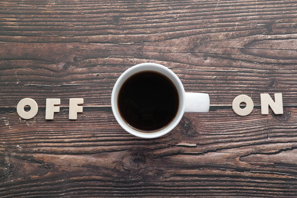 Cup of coffee on wooden desk, switched on, concept. - Photo, image