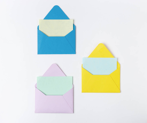 Set of Three of colorful blank envelopes for invitation, on light background with blank card. Minimalist styled composition, top view - Φωτογραφία, εικόνα