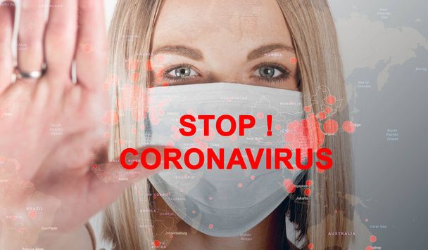 Close-up portrait of woman in medical mask with the inscription STOP Coronavirus with outstretched arm symbolizing the word STOP. - Фото, изображение
