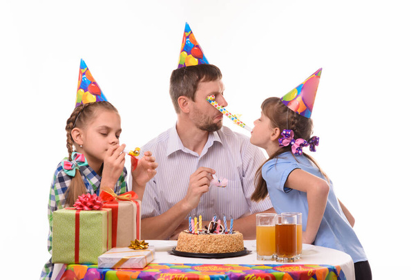 Ragazza ottenuto negli occhi di papà soffiando un tubo festivo a una festa di compleanno
 - Foto, immagini