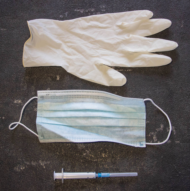 Coronavirus e controllo influenzale. Maschera medica, siringa con ago e guanti di gomma su sfondo nero
.  - Foto, immagini