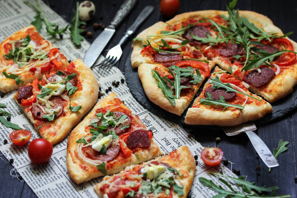 Italian cuisine concept, pizza pepperoni with sausage and arugula on a dark wooden background - Fotó, kép