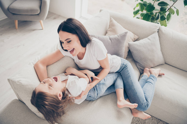 Top above high angle view photo of ideal candid mother daughter relationship mommy and her kid play tickle lay divan in apartment indoors - Foto, Imagem