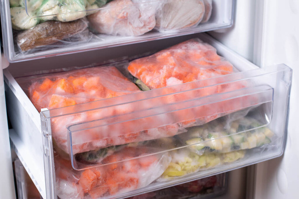Пластикові пакети з різними замороженими овочами в холодильнику, горизонтальні
 - Фото, зображення