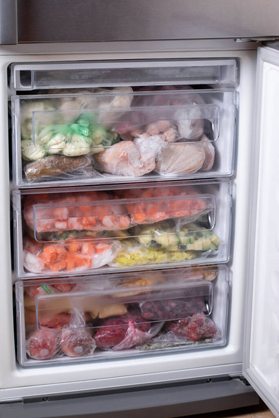 Frozen food in the refrigerator. Vegetables on the freezer shelves. - Photo, Image