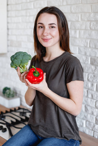 slender girl holding red bell pepper and broccoli - Фото, изображение