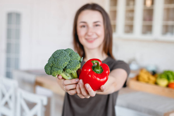 štíhlá dívka drží červenou papričku a brokolici - Fotografie, Obrázek