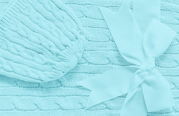 Chapéu de malha de bebê em um cobertor de hortelã macio. Presente bonito para bebê recém-nascido com arco. Espaço de cópia
 - Foto, Imagem