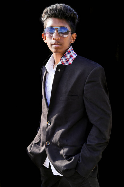 stylish young businessman wearing a modern suit, standing on the black background - Foto, Imagen