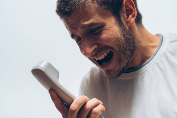 Close-up beeld van een man schreeuwen aan de telefoon tijdens het gesprek. - Foto, afbeelding