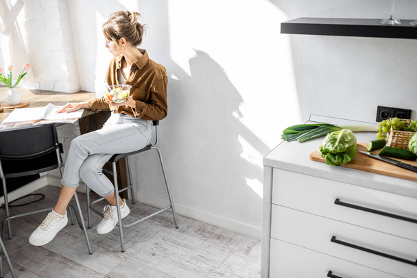 Kobieta jedząca sałatkę w kuchni - Zdjęcie, obraz