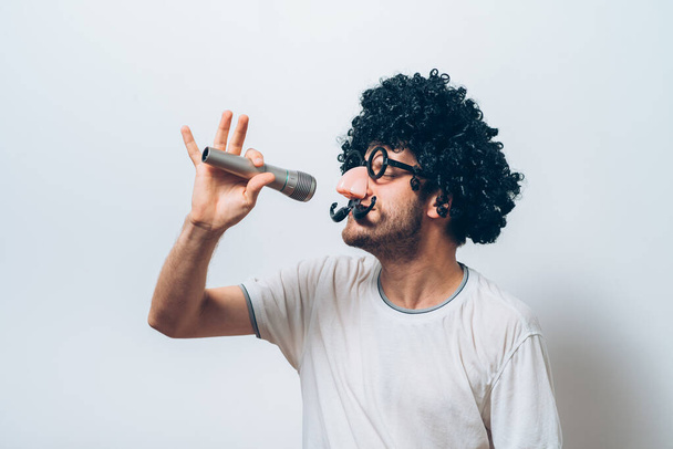 A man in a wig and funny glasses, singing into the microphone - Foto, immagini