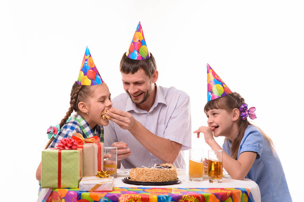 Dad and kids have fun eating cake at the festive table - Photo, Image