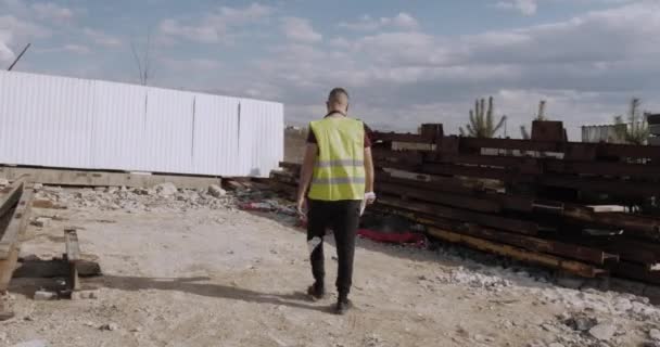 A working man, engineer, walks the construction site with the plan in hand and checks the progress of the works. Investments in construction. - Footage, Video