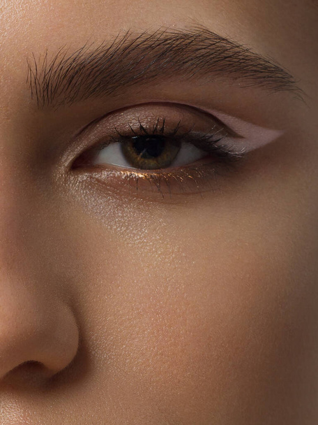 Elegance detailní ženské oko s tmavohnědým očním stínem. Makro záběr části obličeje krásné ženy. Wellness, kosmetika a make-up. hladké krásné obočí a řasy - Fotografie, Obrázek