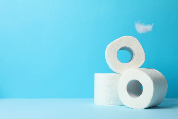 Mavi arkaplanda tuvalet kağıdı ve tüyler, metin için boşluk - Fotoğraf, Görsel