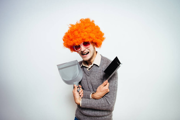 guy with a brush and dustpan in a wig - Φωτογραφία, εικόνα