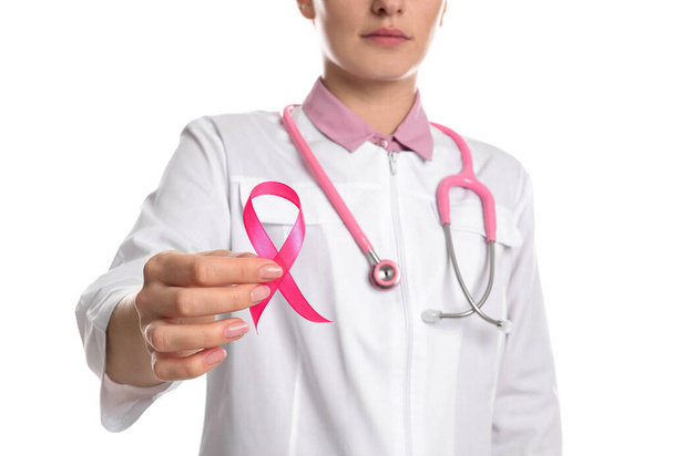 Dokter met roze lint en stethoscoop op witte achtergrond, close-up. Bewustwording van borstkanker - Foto, afbeelding