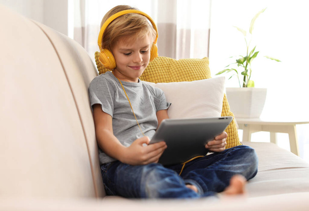 Cute little boy with headphones and tablet listening to audiobook at home - Foto, Imagem