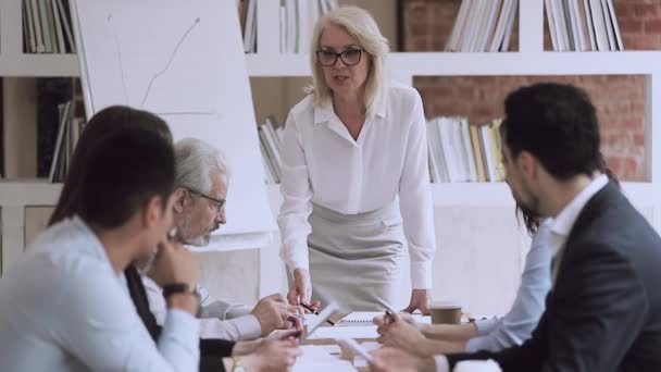 Old female boss talking at group meeting pointing at paperwork - Materiaali, video