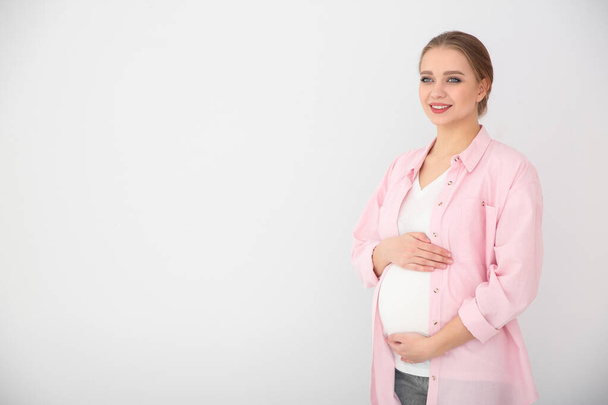 Mujer embarazada joven sobre fondo blanco. Espacio para texto
 - Foto, imagen