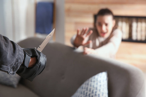 Man threatening victim with knife indoors, closeup. Dangerous criminal - Foto, afbeelding