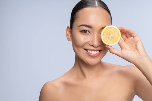 Positive delighted female posing on camera with lemon - Φωτογραφία, εικόνα