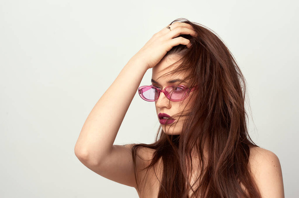 schönes junges Mädchen mit braunen Haaren in modischer Brille posiert auf weißem Hintergrund mit nackten Schultern, leerer Raum für Text - Foto, Bild