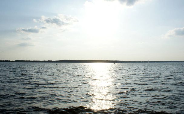 the sun shines strongly on the lake in center - Photo, Image
