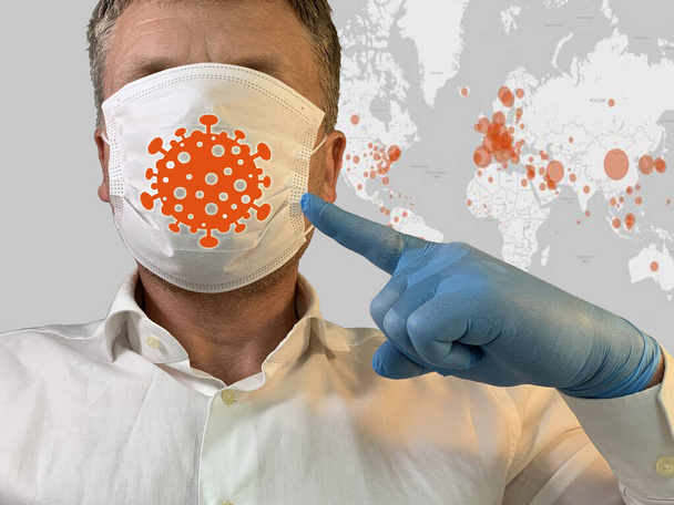 Dünya haritası geçmişinde tıbbi maskeli bir adam. Erkek yüzü koruyucu bir tıbbi maskeyle kaplıdır. Konsept: koronavirüs salgını, zatürree yayılması, salgın hastalık, Covid-19 - Fotoğraf, Görsel