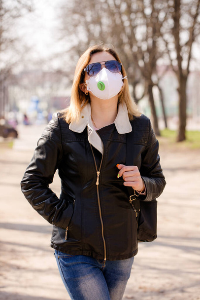 Una joven con una máscara protectora está caminando. Concepto de protección contra el coronavirus
 - Foto, imagen