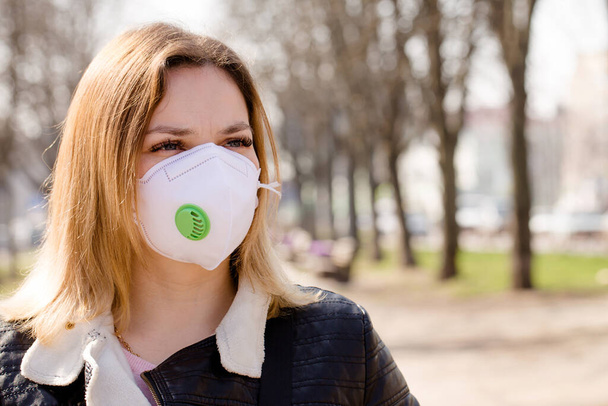 Young beautiful woman in a protective mask walks outdoors. Coronavirus Protection Concept - Zdjęcie, obraz