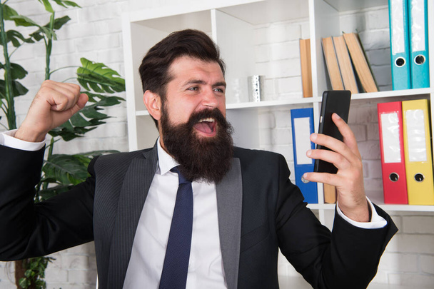 Lost his temper. Angry broker punch smartphone. Bearded man got angry with sms information. De-stressing method. Stress relief in workplace. Feeling angry. Bad mood. Angry conversation via phone - Фото, изображение