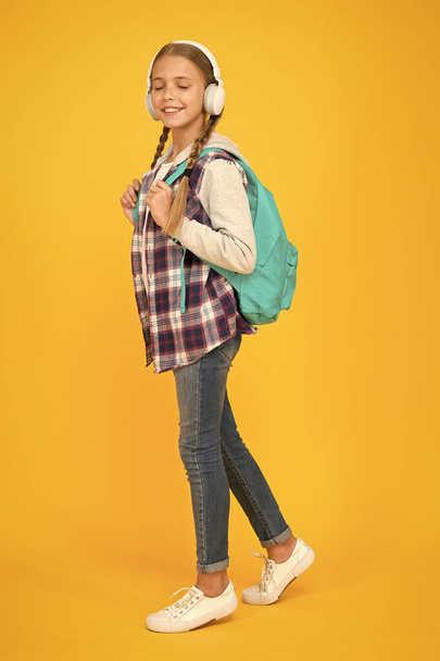 hipster girl care backpack. schoolgirl casual style hold school bag. autumn kid fashion. child listen music headset. childhood education and development. happy childrens day. audio book - 写真・画像