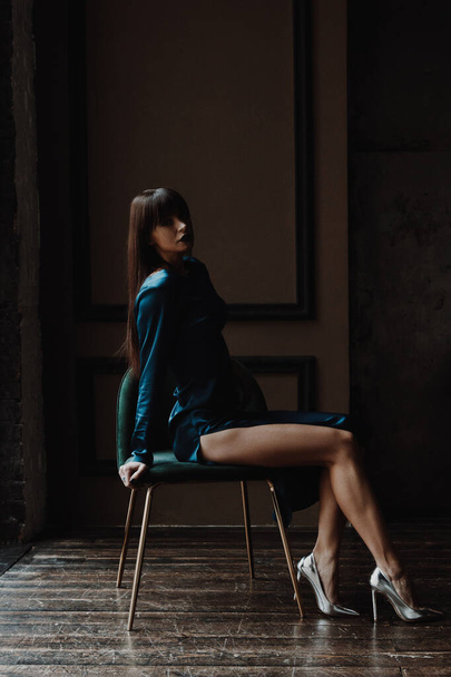 Beautiful young woman in blue dress sitting on chair - Foto, Bild