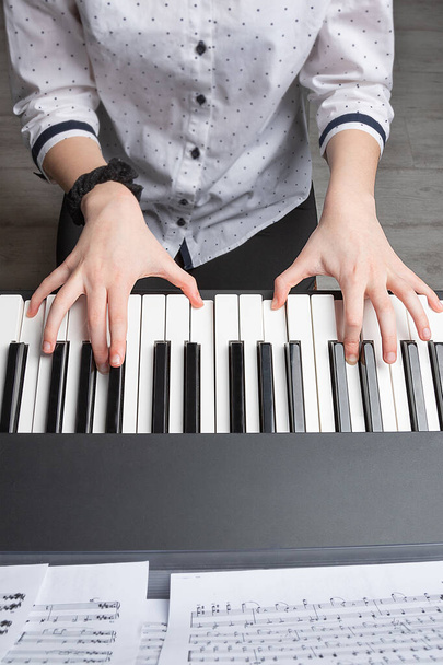 Tyttö soittaa pianoa. Tytön kädet syntetisaattorin avaimilla. Pysy kotona.
 - Valokuva, kuva