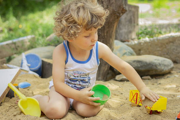 Dítě si hraje venku na pískovišti. Malý chlapec si hraje na dvorku. - Fotografie, Obrázek