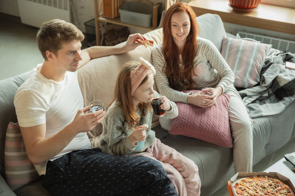 Η οικογένεια περνάει ωραία μαζί στο σπίτι, φαίνεται χαρούμενη και χαρούμενη, τρώγοντας πίτσα. - Φωτογραφία, εικόνα