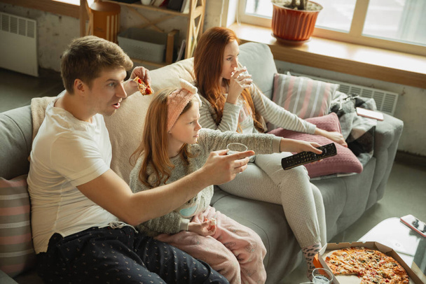 Family spending nice time together at home, looks happy and cheerful, eating pizza - Zdjęcie, obraz