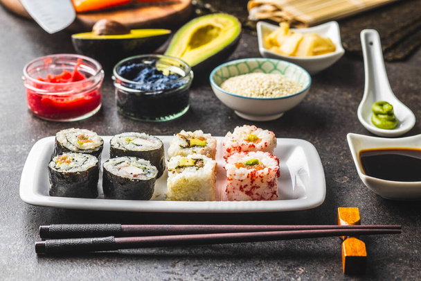Japán sushi kaja. Maki és kaliforniai tekercs sushi lazaccal, kaviárral, avokádóval, tonhallal és wasabival gyömbérrel. - Fotó, kép