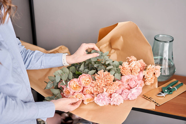Женщина распаковывает цветы на деревянном столе. Свежие срезанные цветы для украшения дома. Цветок доставки
. - Фото, изображение