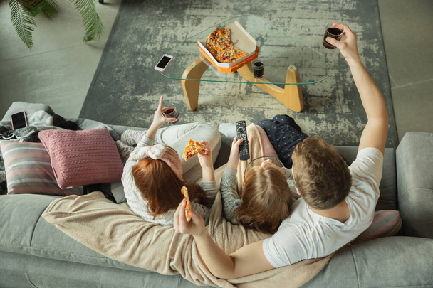 Family spending nice time together at home, looks happy and cheerful, eating pizza. Top view. - Foto, Imagen