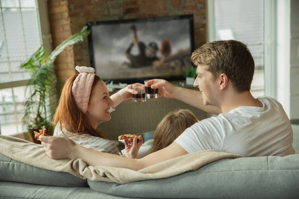 Family spending nice time together at home, looks happy and excited, eating pizza, watching football match - Photo, Image