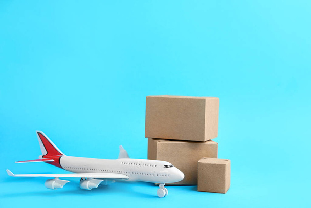 Flugzeugmodell und Kartons auf hellblauem Hintergrund. Kurierdienst - Foto, Bild