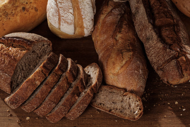 freshly baked bread on wooden kitchen table, close up - Zdjęcie, obraz